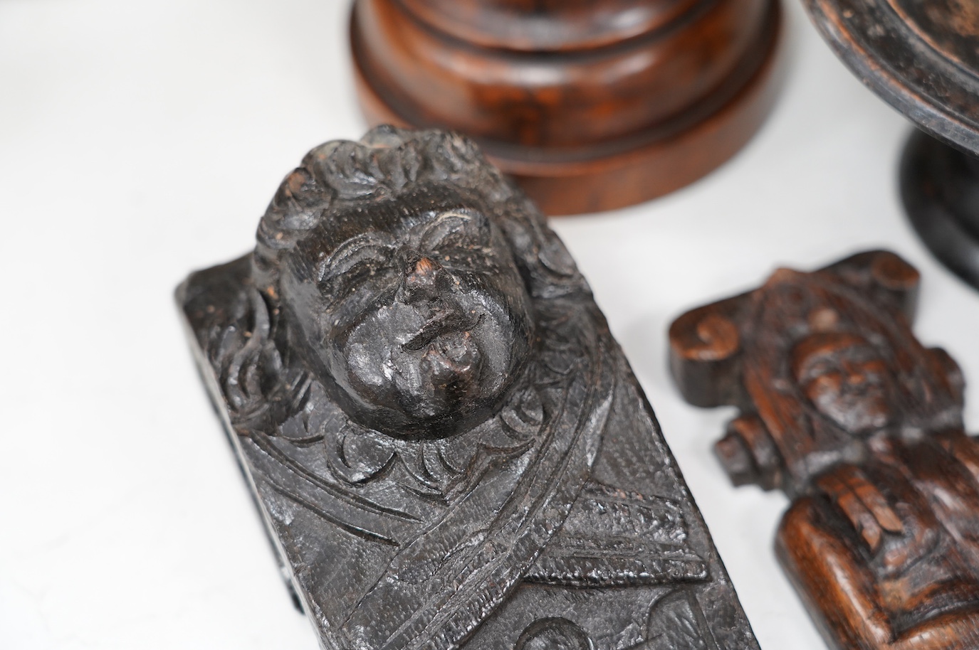 A 17th century carved oak mask corbel, another smaller, a small tazza and a carved wood pot and cover, tallest 19.5cm. Condition - fair to good